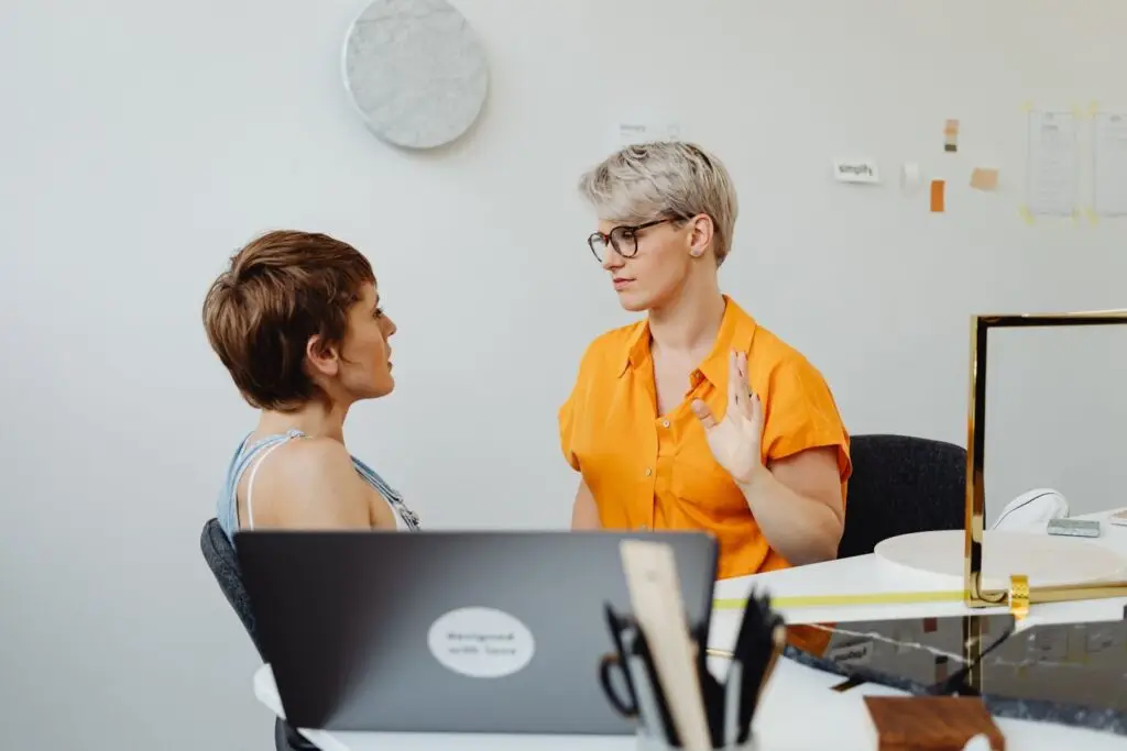 Twee vrouwen overleggen aan een bureau met laptops