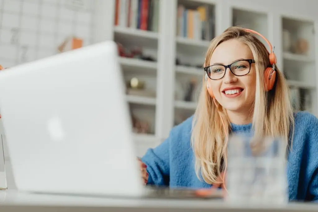 Vrouw met koptelefoon glimlacht tijdens een online gesprek achter een laptop